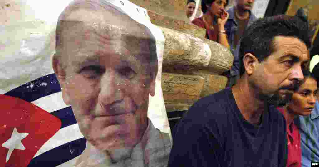 HAB02 LA HABANA (CUBA) 03/04/05.- Un hombre permanece sentado junto a una imagen del Papa Juan Pablo II durante la misa celebrada, hoy domingo 03 de abril, en La Catedral de La Habana, por el cardenal cubano Jaime Ortega y Alamino en homenaje al Sumo Pont