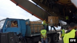 Trabajadores cubanos descargan paquetes de ayuda humanitaria.