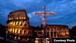 Una enorme cruz iluminada con velas se recorta contra las ruinas del Coliseo romano durante el via crucis nocturno del Viernes Santo de 2014