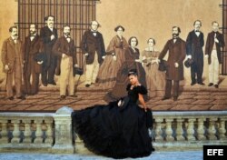 Una joven posa junto a un mural con personajes históricos para las fotos de sus quince años.