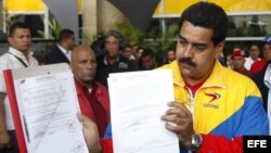 El presidente encargado de Venezuela, Nicolás Maduro (d), muestra su hoja de inscripción como candidato presidencial. 