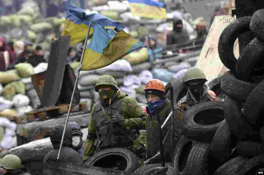 Varios manifestantes permanecen junto a una barricada en otra jornada de protestas antigubernamentales en Kiev (Ucrania).