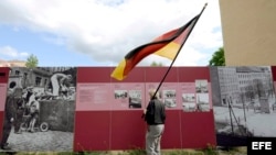 Un hombre con la bandera nacional observa el memorial del Muro de Berlín en Bernauer Strasse, Berlín Alemania. Archivo.