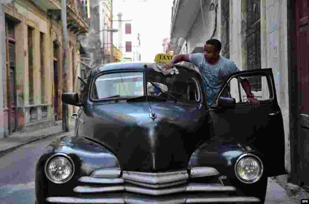 Un hombre limpia su taxi antes de iniciar labores en una calle de La Habana (Cuba), este viernes, 20 de enero de 2017, día en que Donald Trump asume la presidencia de EEUU. &nbsp;