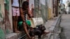 Un hombre baña a su perro en la puerta de su casa en La Habana. (AP Photo/Ramon Espinosa)