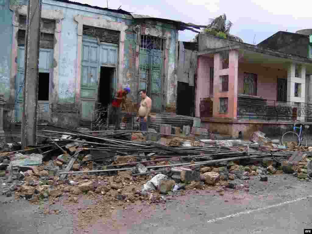 Dos hombres limpian escombros en una casa que ha sido parcialmente destruida por el paso del huracán "Sandy".