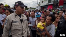 Un hombre con un niño en brazos grita consignas a un miembro de la Policía Nacional Bolivariana (PNB), durante una protesta para exigir alimentos en el sector popular Catia, en Caracas (Venezuela). 