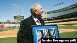 Tommy John muestra la foto de la operación a la que fue sometido, durante un homenaje de los Dodgers en 2014.
