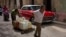 Cubanos trasladando envases de agua frente a un viejo auto estadounidense en La Habana. Foto AP/Ramón Espinosa. 