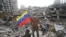 Un rescatista voluntario se encuentra junto a una bandera venezolana sobre los escombros de un edificio colapsado en Caraballeda, estado de La Guaira, Venezuela, el 15 de julio de 2026, tras los terremotos gemelos del 24 de junio.