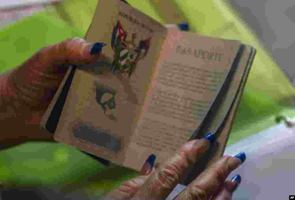 Danmara Triana muestra su pasaporte en su casa en Cienfuegos, Cuba, el 19 de mayo de 2022. Su esposo y su hijo viven en Estados Unidos desde 2015, mientras que ella y sus dos hijas se quedaron en Cuba. (AP Foto/Ramón Espinosa)