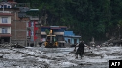 Un residente camina por una calle cubierta de barro tras unas inundaciones repentinas y un deslizamiento de tierra en Devighat, en el distrito nepalí de Nuwakot, el 26 de agosto de 2026.