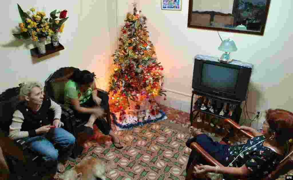 Tres mujeres conversan en una casa decorada con un árbol de Navidad. 