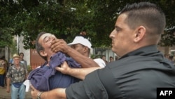 El periodista independiente Lázaro Yuri Valle es sometido por las autoridades en plena vía pública, el 10 de diciembre de 2015. (AFP/Adalberto Roque)