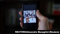 Un hombre que no quiso ser identificado muestra en su teléfono al rapero contestatario Maykel Castillo El Osorbo. (REUTERS/Alexandre Meneghini) 