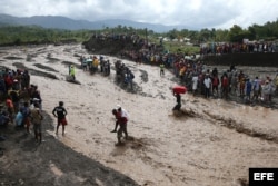 Personas intentan cruzar el río La Digue, debido al derrumbe del único puente que conecta con el sur, tras el paso del huracán Matthew hoy, 5 de octubre de 2016, en Petit Goave (Haití). El impacto del huracán Matthew en Haití, donde dejó al menos nueve mu