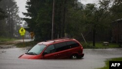 En esta foto del viernes, una minivan abandonada se ve semisumergida en una carretera inundada cerca de New Bern, Carolina del Norte 