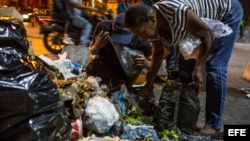 Varias personas buscan comida entre bolsas de basura en Caracas. (Archivo)