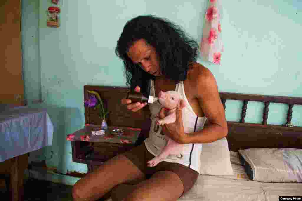 Charito, alimentando a un cerdito de una semana de nacido en su casa de Camagüey. 