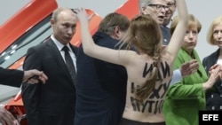 Vladimír Putin (i), y la canciller alemana, Angela Merkel (2-d), se ven sorprendidos por una activista de Femen en topless durante su visita a la Feria Industrial de Hanover, Alemania. 