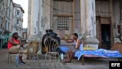 Dos hombres cuya vivienda fue severamente afectada por el huracán Irma conversan junto a sus pertenencias en el malecón de La Habana.