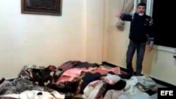 Un hombre de pie junto a los cadávares de varias personas que él denuncia fueron asesinadas por el ejército sirio en Homs (Siria).