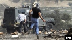 Palestinos lanzan piedras a un vehículo policial israelí durante un protesta contra el asentamiento judío de Kedumim, en Cisjordania.