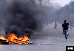 Manifestantes pasan junto a una barricada durante la marcha organizada por la oposición en Puerto Príncipe, Haití.