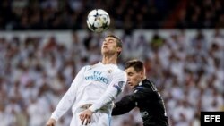 Cristiano Ronaldo (i), del Real Madrid, salta por el balón junto a Lo Celso, del Paris Saint Germain.