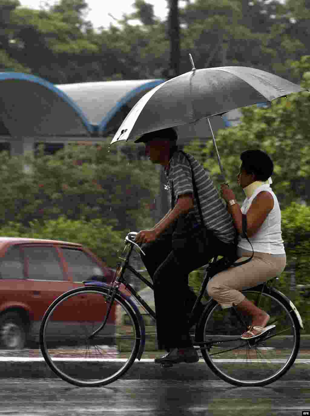 Una pareja transita en bicicleta bajo una fuerte lluvia en La Habana.