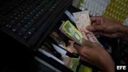 Un hombre guarda dinero en una máquina registradora en Caracas (Venezuela).