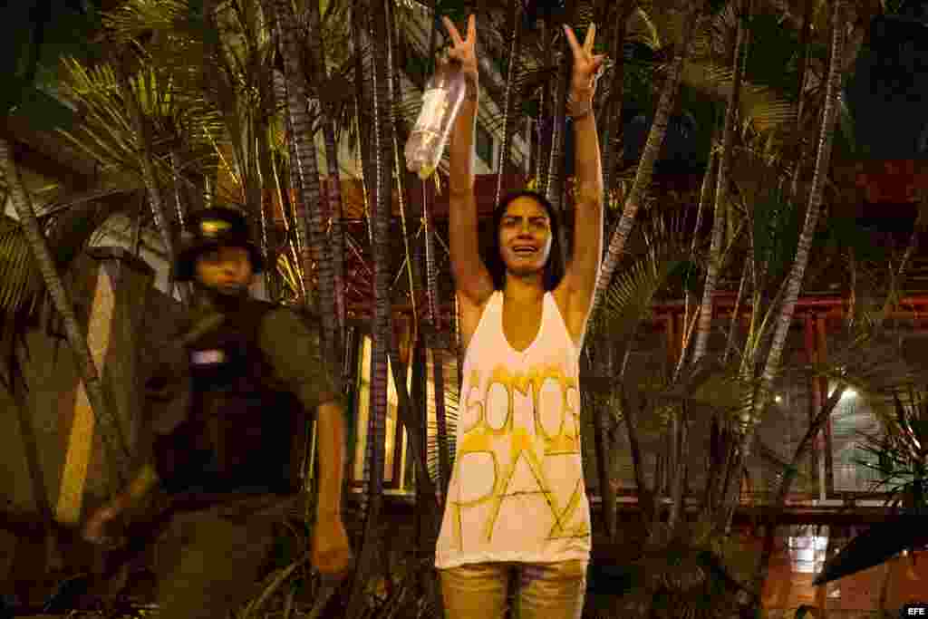 Una mujer hace un llamado a la paz mientras protestantes se enfrentan con miembros de la Guardia Nacional Bolivariana (GNB.