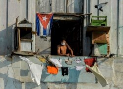 Un hombre con una máscara protectora desde su balcón en La Habana. (YAMIL LAGE / AFP)