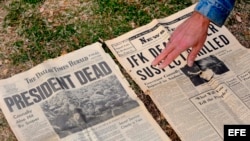 A man points to a 1963 newspaper announcing the death of JFK. 