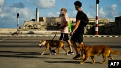 Hombres con mascarillas de protección corren por el Malecón de La Habana. (Yamil LAGE / AFP)