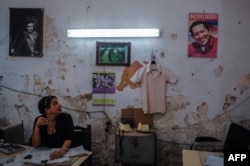Una mujer mira la fotografía de Fidel y Raúl Castro en su oficina.