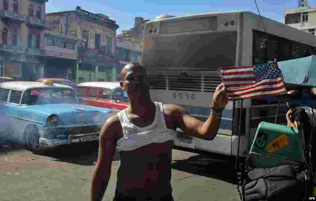 Un joven muestra la bandera de Estados Unidos que tiene en su bicitaxi .