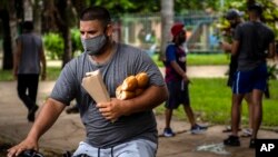 Un hombre carga el pan mientras viaja en bicicleta en Bauta, Artemisa. (AP/Ramon Espinosa)