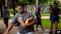 Un hombre carga el pan mientras viaja en bicicleta por una calle de La Habana. (AP/Ramon Espinosa)