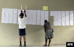 Dos personas buscan sus nombres en las listas de electores en un centro de votación en Puerto Príncipe.