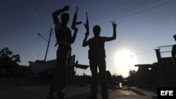 Rebeldes sirios hacen signos de victoria en la base militar de Tecvid Sicco, al norte de la ciudad siria de Aleppo. 