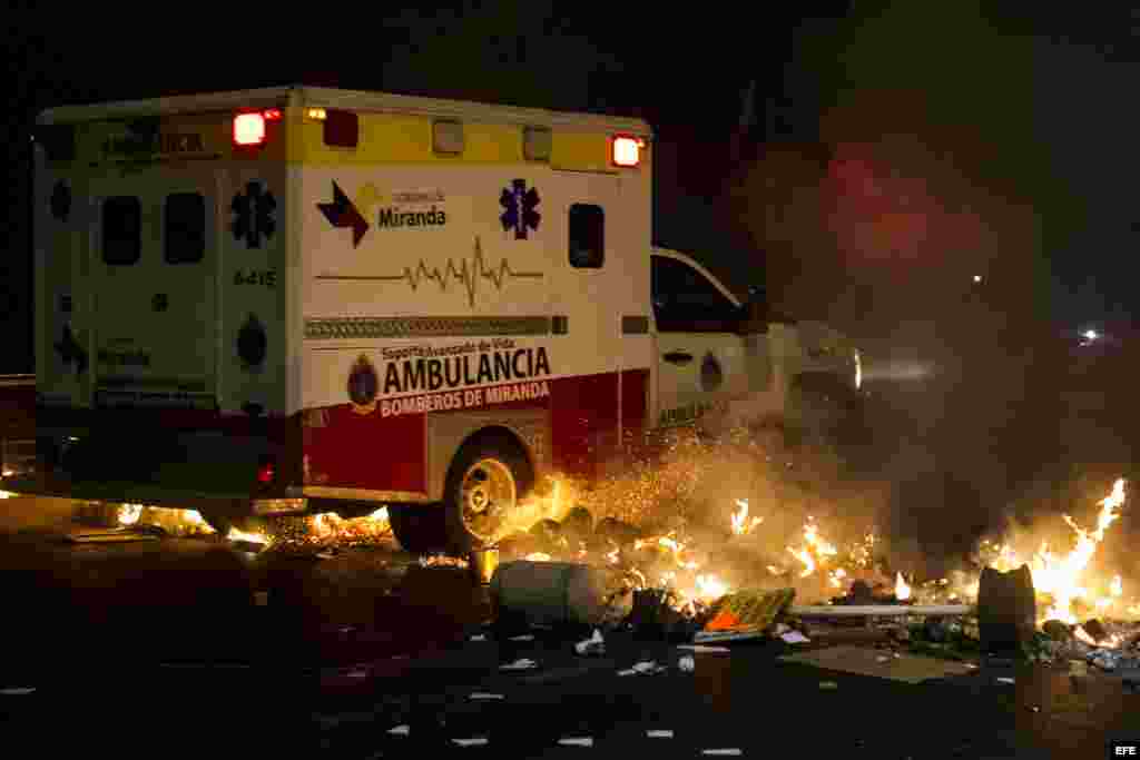 Una ambulancia cruza una barricada de fuego mientras protestantes se enfrentan con miembros de la Guardia Nacional Bolivariana (GNB).