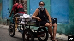 Una mujer viaja en un triciclo por una calle de La Habana tras comprar algunos alimentos en un mercado estatal. (AP/Ramon Espinosa)