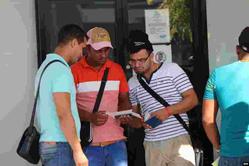 Tres cubanos revisan sus documentos hoy, miércoles 10 de febrero de 2016, que les permiten comprar el boleto de avión, por 523,50 dólares cada uno, para viajar a México. 