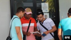 Tres cubanos revisan los documentos que les permiten comprar el boleto de avión, por 523,50 dólares cada uno, para viajar a México. 