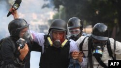El periodista venezolano de VPITV Gregory Jaimes (C) recibe asistencia de colegas luego de ser heridos durante los enfrentamientos entre manifestantes antigubernamentales y fuerzas de seguridad en la conmemoración del Primero de Mayo en Caracas el 1 de ma