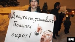 Un manifestante sujeta un cartel en el que se puede leer 'Legisladores, adoptad niños enfermos' durante una manifestación en contra de la ley que prohíbe adoptar niños a Estados Unidos, en San Petersburgo, Rusia. 