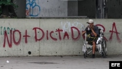 Un hombre en condición de discapacidad reacciona ante los gases lacrimógenos durante una manifestación en Caracas.