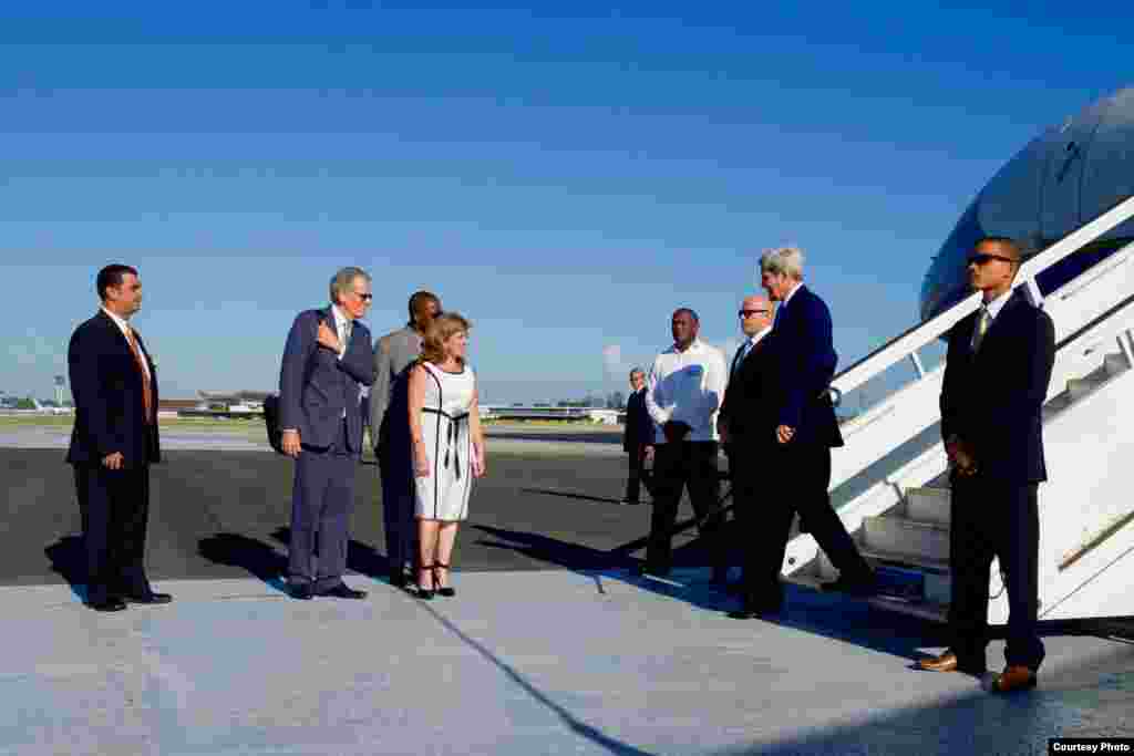 John Kerry es recibido en La Habana por la subdirectora de protocolo del Ministerio de Relaciones Exteriores de Cuba, Lydia González Navarro, y por Jeffrey DeLaurentis, encargado de negocios de la embajada estadounidense.