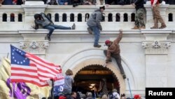 Una turba de simpatizantes del expresidente Donald Trump lucha contra policías en la puerta que rompieron al asaltar el Capitolio en Washington D.C. el 6 de enero pasado.